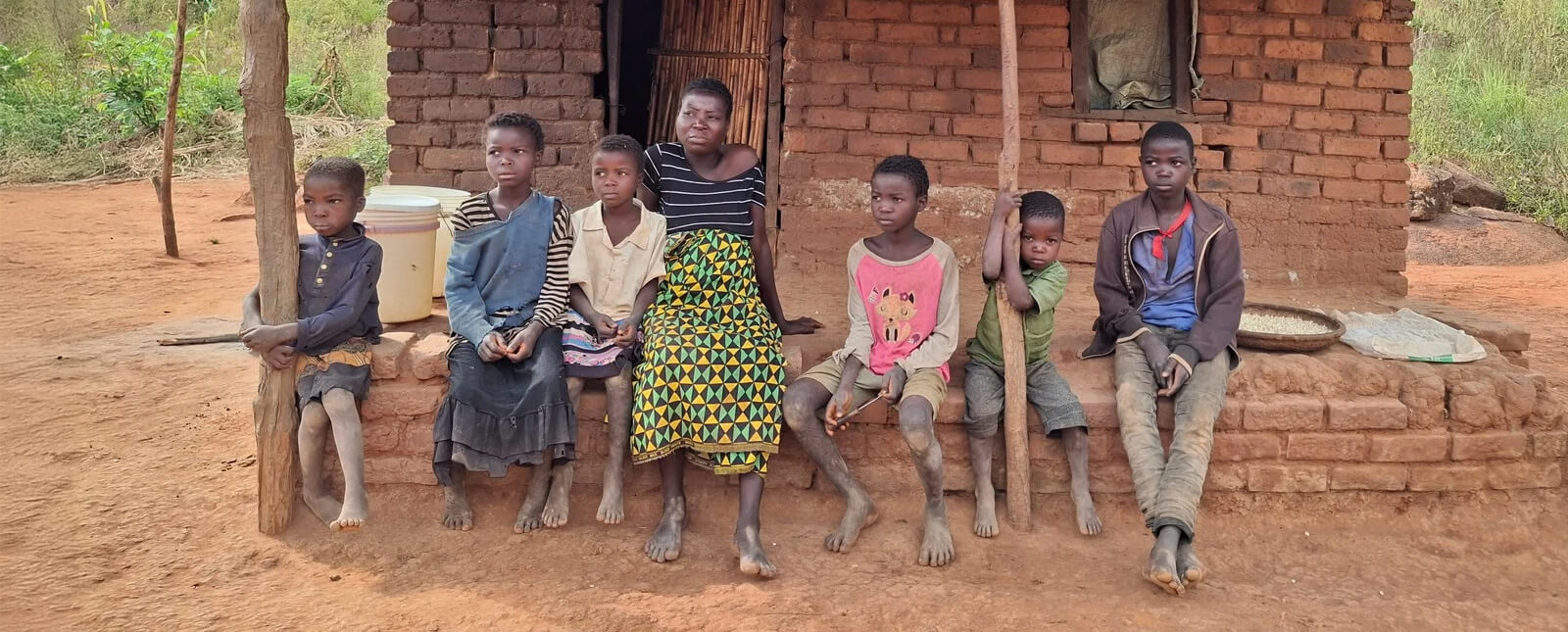 rodina sedí před hliněným domem