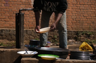 Chlapec umývá talíř. Nápravné zařízení. Madagaskar.